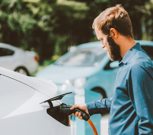 Bearded man with an EV charger in a white car