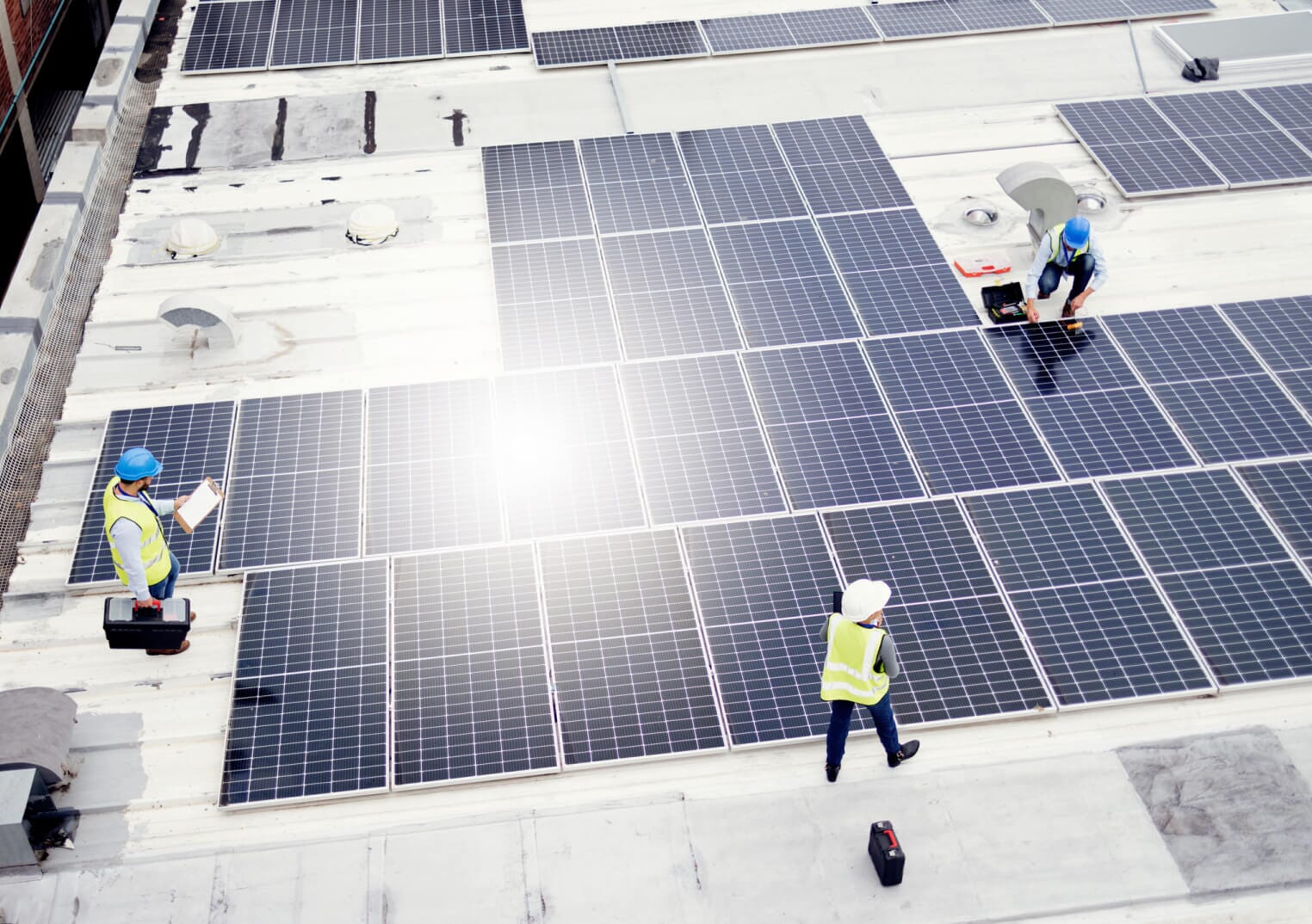 Three workers on solar roof, in hardhats
