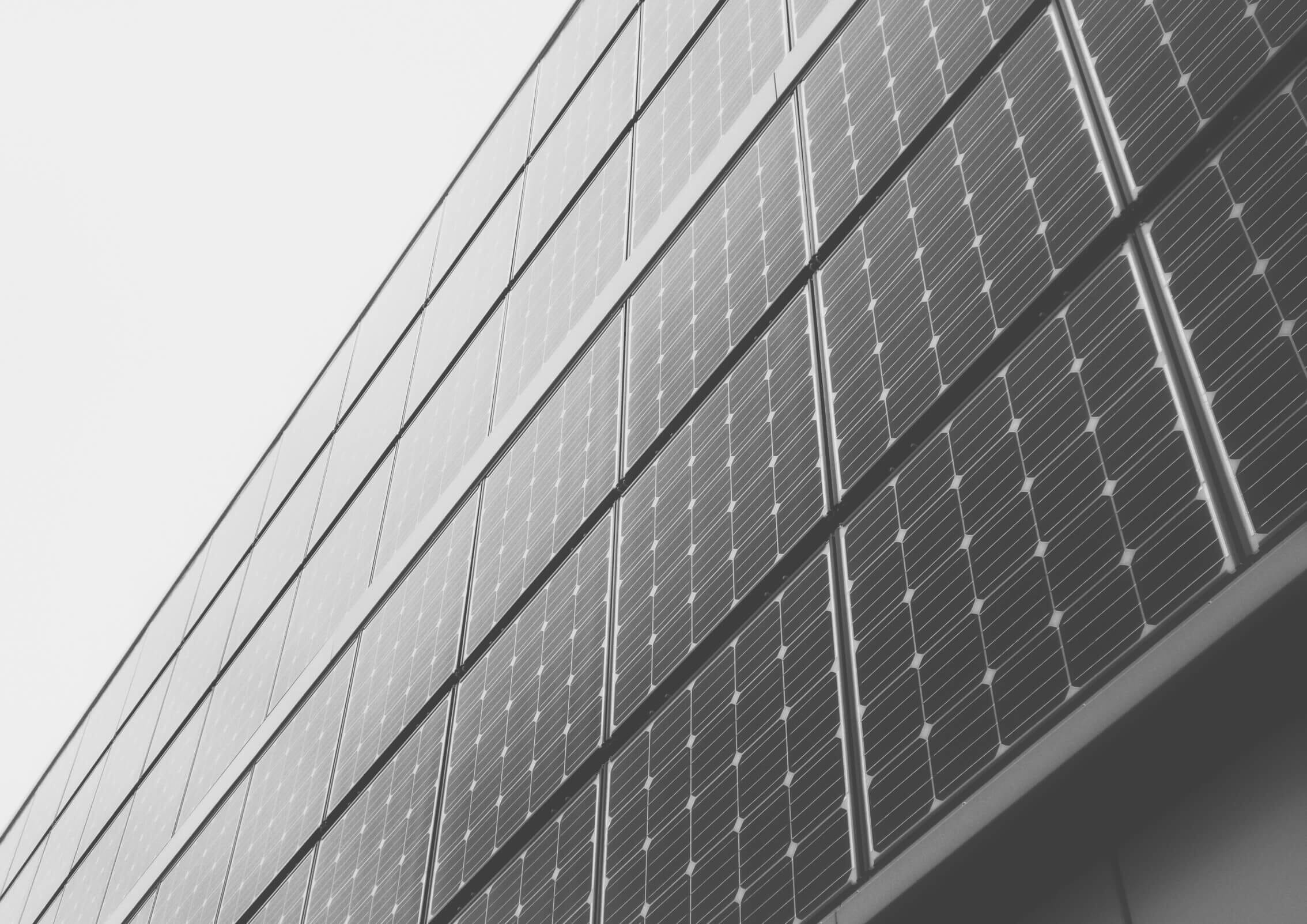 Close up image of commercial solar panels with a grey sky background